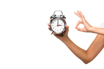 partial view of woman holding alarm clock, isolated on white