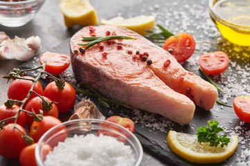 Fototapeta na wymiar raw fresh salmon with seasoning and tomatoes on stone board