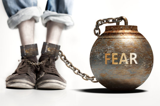 Fear can be a big weight and a burden with negative influence - Fear role and impact symbolized by a heavy prisoner's weight attached to a person, 3d illustration