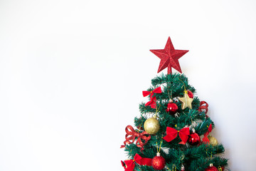 Red Christmas star on top of Christmas tree decorated with balls and bows isolated on white background. Concept of merry christmas, holidays, happy new year, gifts, happiness and celebration.