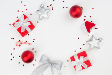 Round frame from red Christmas gifts, balls, star confetti, candy cane on white background. Congratulation, Happy New Year concept. Top view, flat lay, copy space