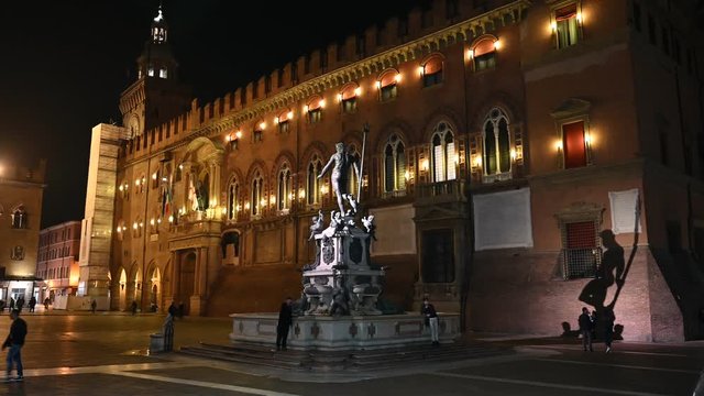 Bologna, Italy - October 2019 - Unknown people walk in the evening among the buildings and monuments of the historic city center, followed by the shadows of the night