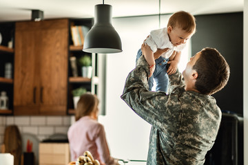 Playful military man having fun with his small son at home. - Powered by Adobe