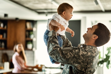 Happy military officer having fun with his baby son at home.