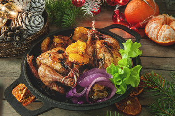 On a wooden table are two cooked carcasses of stuffed quail in tangerine sauce for Christmas dinner. Christmas dinner at home