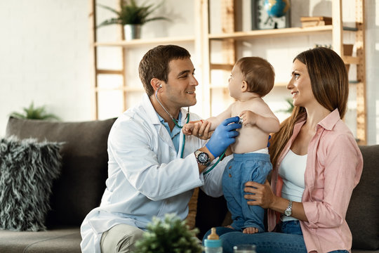 Smiling pediatrician listening small boy's heartbeat during medical examination.