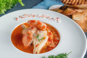 Diet soup of seafood and fish of different varieties in a white plate. Close up
