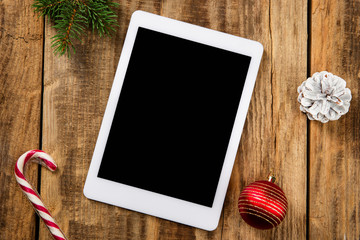 Mock up blank empty screen of tablet on the wooden background with colorful holiday's decoration and gifts. Copyspace, negative space for your advertising. 31 of December, New Year concept.