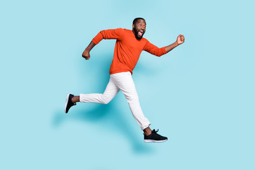 Fototapeta na wymiar Photo of cheerful positive excited crazy running jumping black man wearing sneakers white trousers pants aspiring for sales isolated vivid blue color background