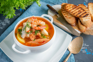 Diet soup of seafood and fish of different varieties in a white soup plate. Close up