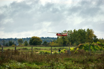 The red light plane lands over the field.