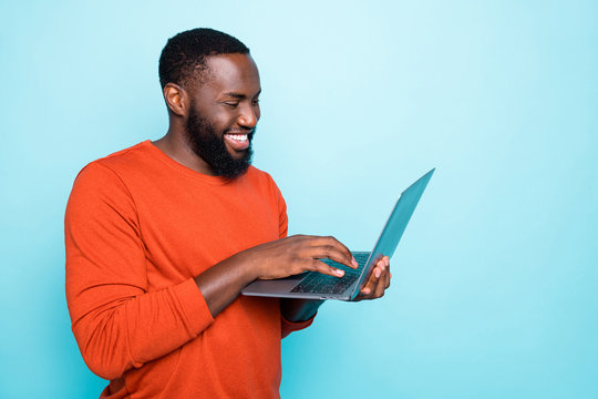 Photo of cheerful man browsing through his laptop smiling toothily making new video which can be watched on his social media isolated vivid blue color background