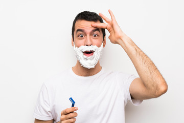 Man shaving his beard over isolated white background has just realized something and has intending the solution