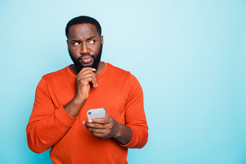 Photo of concentrated man focused on recollecting neccessary facts browsing thorugh telephone he holds isolated vivid color blue background