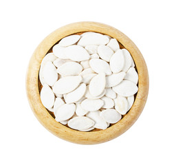 Dired pumpkin seeds with shell on wooden dish.