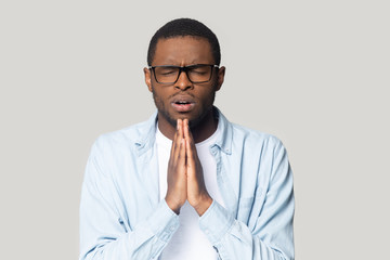 Head shot upset African American man joining hands in prayer