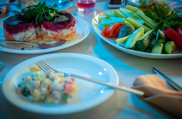 Traditional new year celebration meals of russian table herring and Olivier salads are on plates in restaurant