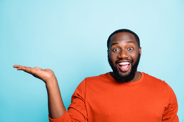 Close up photo of funny dark skin guy holding open palm empty space advising new product with low...