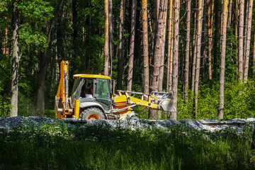 Excavator works on the construction of the railway in the forest. Yellow excavator pours the gravel...