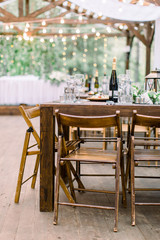 Wedding dinner table decoration outdoors in forest. Wooden table setup for wedding party or dinner reception. Rustic decorations on the table