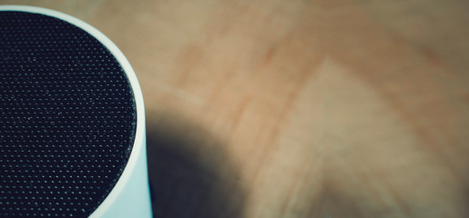 Closeup of an auido speaker on a wooden table.  Blurred background as copy space.
