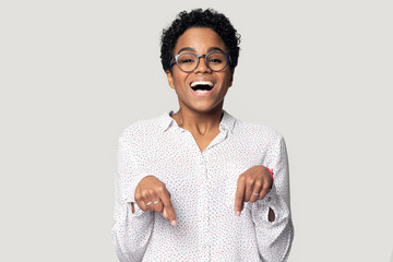 Head shot excited African American girl in glasses pointing down