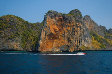 Boat on the background of the rainforest on the cliff.