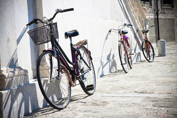 Three old bicycles against a marble wall (Tuscany - Italy)