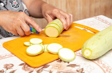 A woman cuts with a knife zucchini