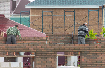 Worker builds a house with bricks at a construction site