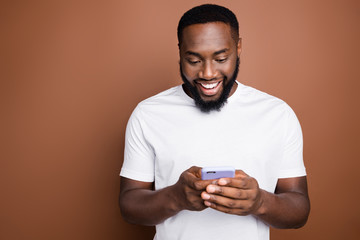 Close-up portrait of his he nice attractive cheerful cheery addicted bearded guy wearing white tshirt browsing reading smm post blog isolated over dark brown platinum pastel color background