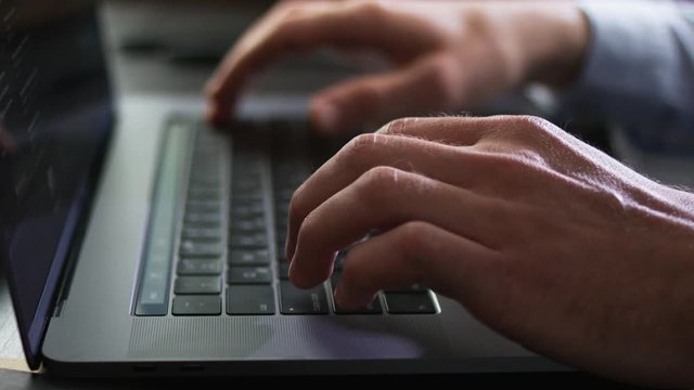 Man works in an office on a laptop, types text on a keyboard