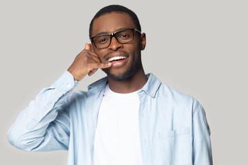 Head shot happy African American man showing call me gesture