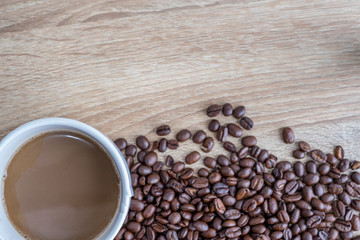 Hot coffee in white glass and roasted coffee beans on wooden boards With space