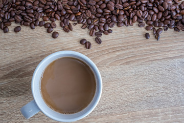 Hot coffee in white glass and roasted coffee beans on wooden boards With space