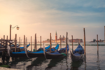 Fototapeta na wymiar Gondolas on the pier. Cathedral of San Giorgio Maggiore on the background. Yearly Venetian morning