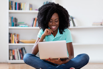Fototapeta na wymiar Laughing african american woman watching movie online with computer