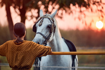 Young woman with her horse in evening sunset