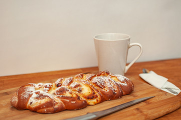 Sliced curd pie with a cup of tea and a knife on a cutting board, photo in bright colors