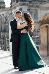 Naklejka premium Concept about love, relationship, and travel. Photo of a lovely couple having fun while traveling in their vacation time. Lady in a green dress. Man in suit. Stylish loving couple pose. Tenderness 