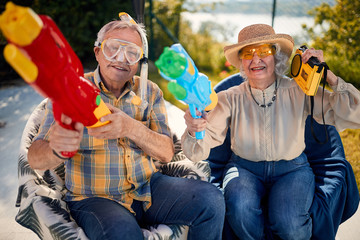 Old people have fun playing with  water gun.