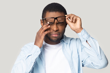 Head shot stressed African American man in glasses touching eyelids