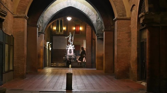 Bologna, Italy - October 2019 - Unknown people walk in the evening among the buildings and monuments of the historic city center, followed by the shadows of the night