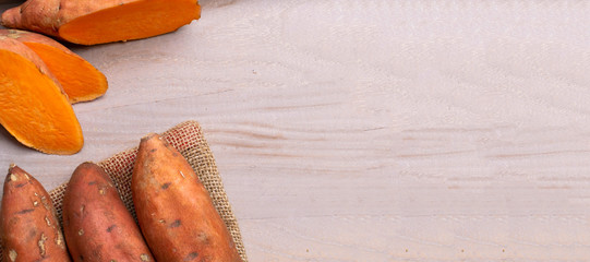 Raw sweet potatoes on wooden background copy space