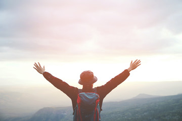 young man hiking traveling standing fist hands up on top of cliff in summer travel Lifestyle wanderlust adventure with backpack on peak mountain. Tourist traveler on background valley landscape view. 