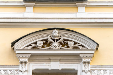 The facade of an ancient building with beautiful stucco on the windows