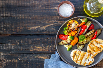 Grilled chicken with grilled vegetables on a wooden background. Healthy eating.