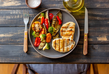 Grilled chicken with grilled vegetables on a wooden background. Healthy eating.