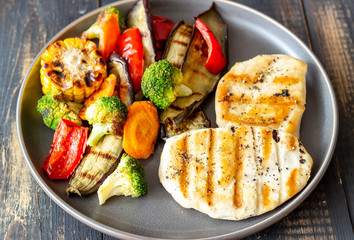 Grilled chicken with grilled vegetables on a wooden background. Healthy eating.