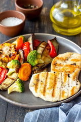 Grilled chicken with grilled vegetables on a wooden background. Healthy eating.